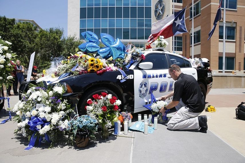 Un hombre coloca una ofrenta en tributo a los policías muertos en el tiroteo de Dallas este jueves 7 de julio. (EFE)