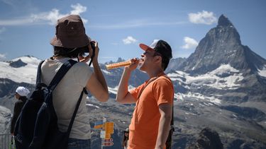 Esta fotografía de archivo tomada el 8 de agosto de 2020 muestra a un turista posando mientras sostiene una barra de chocolate suizo de la marca Toblerone, propiedad del gigante estadounidense de alimentos Mondelez International en Gornergrat, con la montaña Matterhorn al fondo, a 3089 metros de altura sobre el balneario de Zermatt. 