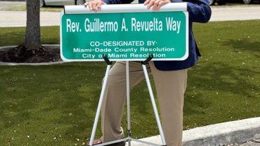 Rev. Guillermo A. Revuelta posa con la placa de la calle a su nombre.&nbsp;