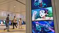 Varias personas caminan junto a vallas publicitarias digitales que anuncian el próximo lanzamiento del videojuego Demon Slayer: Kimetsu no Yaiba – The Hinokami Chronicles 2, a lo largo de un pasillo dentro de una estación de tren en el centro de Tokio el 29 de julio de 2025.
