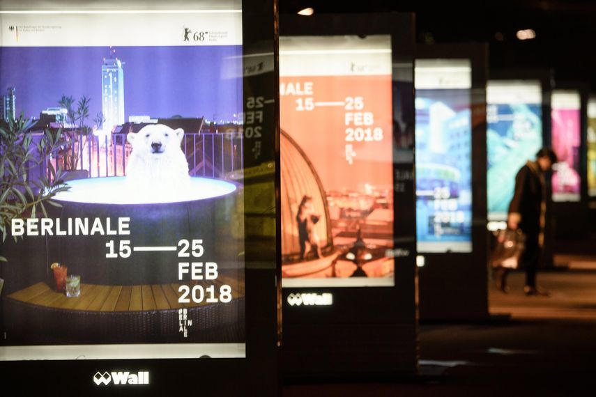 Un peatón camina frente a carteles promocionales del Festival Internacional de Cine de Berlín.