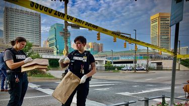 Un equipo de forenses recolecta evidencia el jueves 7 de julio de 2022 en el lugar donde un hombre murió baleado después de tratar de golpear con un bate de béisbol a una persona que limpiaba parabrisas en una intersección de Baltimore. 