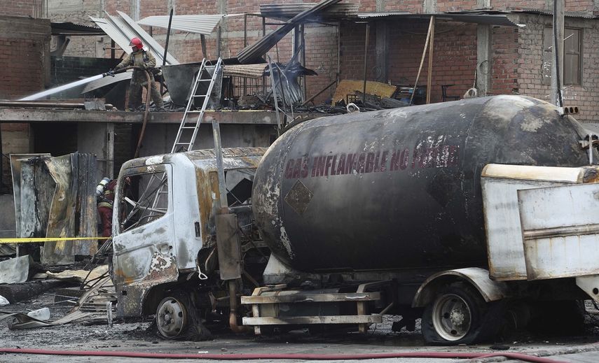 Un bombero enfr&iacute;a con agua el techo de un cami&oacute;n cisterna de gas que explot&oacute; en el barrio de Villa Mar&iacute;a en Lima, Per&uacute;, el jueves 23 de enero de 2020. La explosi&oacute;n dej&oacute; dos muertos, aproximadamente 50 personas heridas y al menos una docena de casas quemadas.&nbsp;