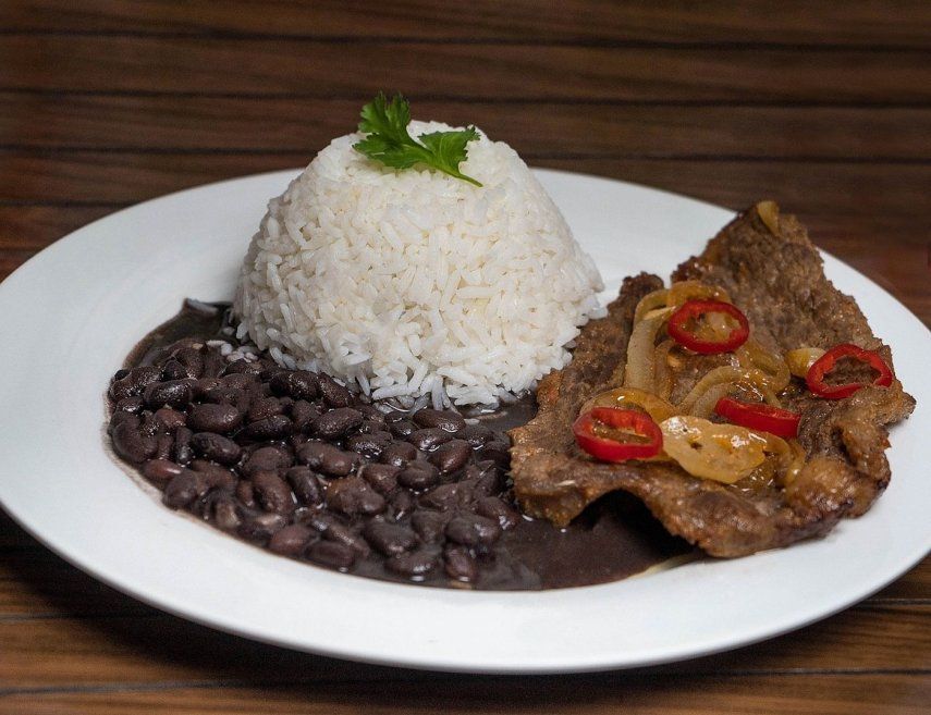 Un plato con frijoles negros, arroz blanco y carne.&nbsp;