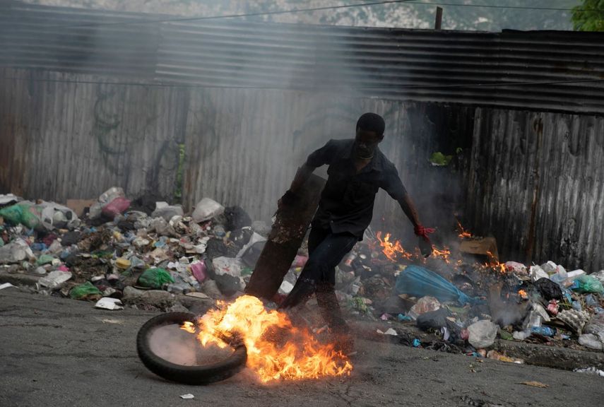 Un manifestante patea un neumático en llamas durante una protesta en Puerto Príncipe, Haití, el lunes 22 de agosto de 2022.