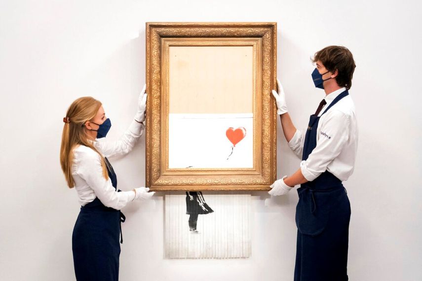 Manipuladores de arte sostienen Love is in the Bin de Banksy en la casa de subastas Sothebys en Londres.&nbsp;
