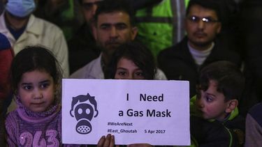 Niños sirios, junto con voluntarios y personal de primeros auxilios muestran pancartas durante una concentración en Douma para mostrar solidaridad con los fallecidos durante el ataque químico del martes pasado.