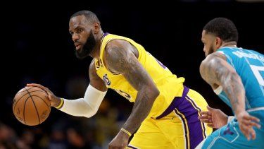 LeBron James (izquierda), de los Lakers de Los Ángeles, maneja el balón en un partido contra los Hornets de Charlotte, el 28 de diciembre de 2023.