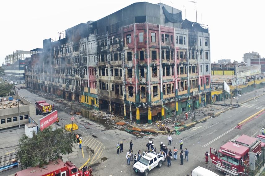 Momento en el que las autoridades policiales trasladan los restos carbonizados de los dos jóvenes que murieron víctimas del incendio en el centro comercial Las Malvinas, en Lima, Perú.