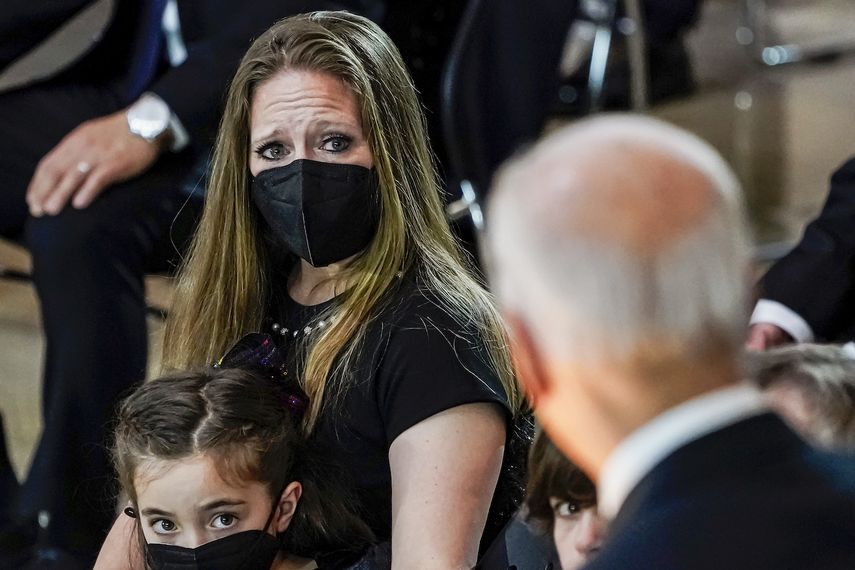Abigail Evans, de 7 años, y Logan Evans, de 9 (abajo a la derecha, semicubierto), hijos del fallecido policía del Capitolio de Estados Unidos William Billy Evans, observan junto a su madre, Shannon Terranova, al presidente Joe Biden (de espaldas) mientras habla durante un homenaje al oficial Evans en la Rotonda de ese edificio el martes 13 de abril de 2021 en Washington.&nbsp;