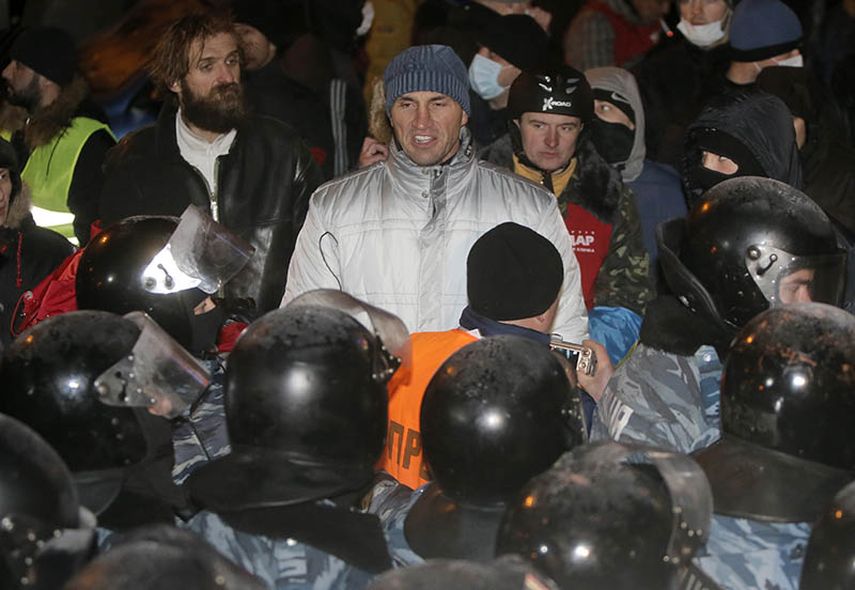 El campeón mundial de boxeo, Vladimir Klitschko (centro) permanece frente a policías antimotines durante las protestas en Kiev, Ucrania, el miércoles (AP)