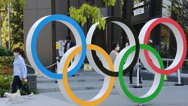 Una mujer y su perro pasan al lado de los aros olímpicos en Tokio, el 20 de abril de 2021