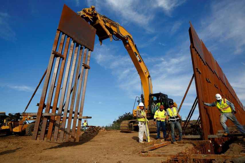 Un equipo de construcción instala una nueva sección del muro fronterizo con México, visto desde Tijuana. &nbsp;