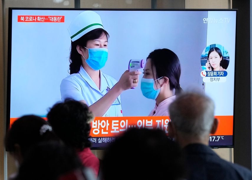 Gente mirando una pantalla de televisión que muestra un reporte noticioso sobre el brote de COVID-19 en Corea del Norte, en una estación de tren de Seúl, Corea del Sur, el sábado 14 de mayo de 2022.