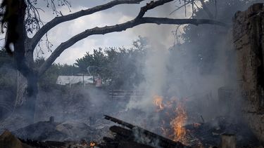 Un residente local (atrás) intenta combatir el fuego en la casa de un vecino, destruida por un ataque ruso el viernes 5 de agosto de 2022 en Mykolaiv, Ucrania.&nbsp;