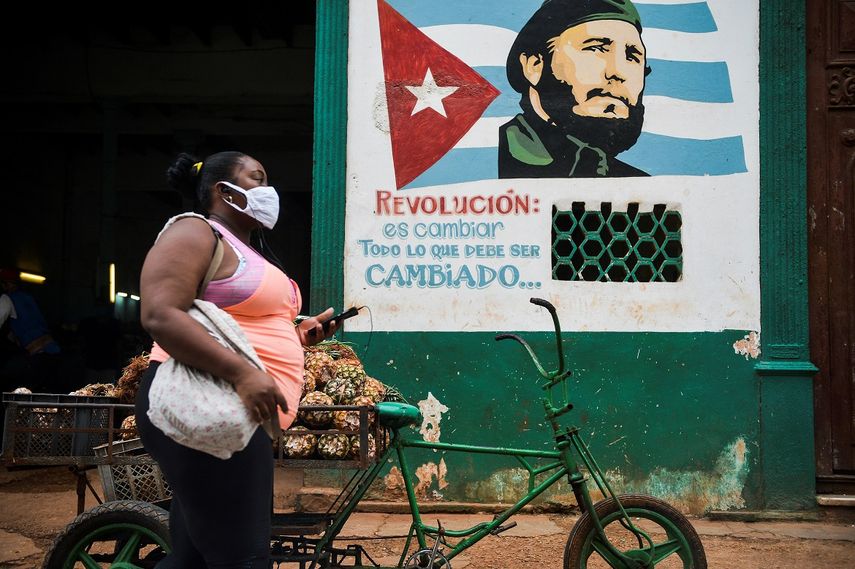 Una mujer con mascarilla camina cerca de un cartel que representa al fallecido líder cubano Fidel Castro en el que se lee “La revolución está cambiando todo lo que hay que cambiar” en La Habana, el 21 de enero de 2021.&nbsp;