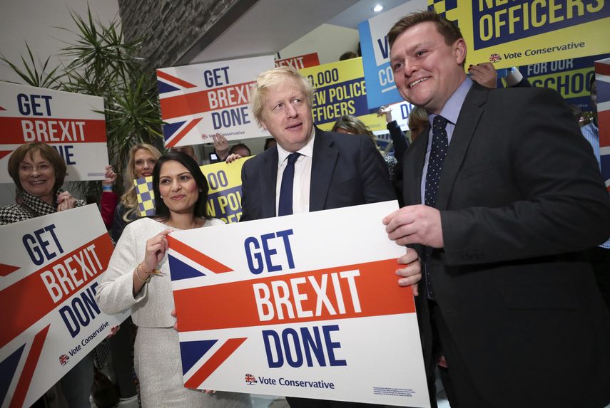 La secretaria brit&aacute;nica de Interior, Priti Patel, en el centro izquierda, el primer ministro brit&aacute;nico, Boris Johnson, en el centro, y el parlamentario Will Quince, posan sosteniendo un cartel antes un mitin, dentro de la campa&ntilde;a para las elecciones generales, en Colchester, Inglaterra, el lunes 2 de diciembre de 2019.&nbsp;