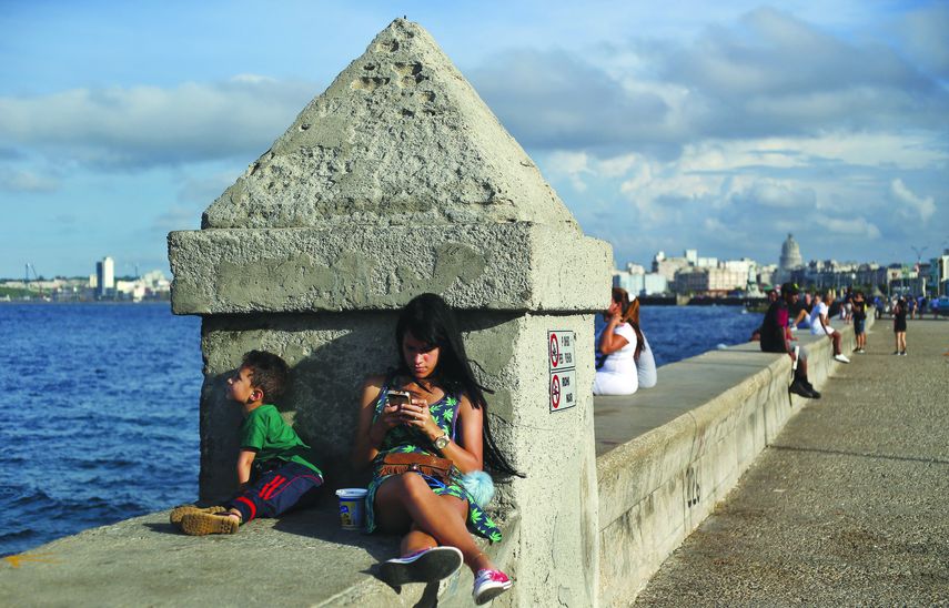 Una joven se conecta a internet sentada en el muro del malecón que bordea una parte de la costa de La Habana.