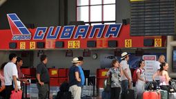 Un grupo de personas espera para abordar un vuelo en el aeropuerto José Martí, de La Habana, frente al logo de Cubana de Aviación.