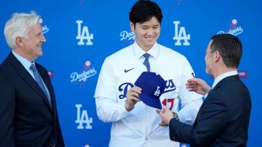 Shohei Ohtani recibe una gorra de manos de Andrew Friedman, presidente de operaciones deportivas de los Dodgers de Los Ángeles, el jueves 14 de diciembre de 2023.