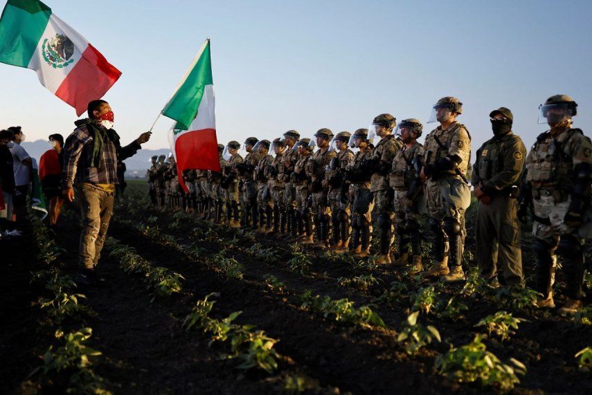 Soldados de la Guardia Nacional bloquean a los manifestantes que ondean bandera de México durante una redada de inmigración de ICE en una granja de cannabis cercana el 10 de julio de 2025 cerca de Camarillo, California.