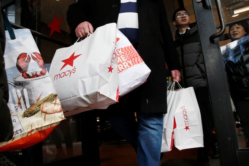 Varias personas salden de una tienda Macys con sus compras.