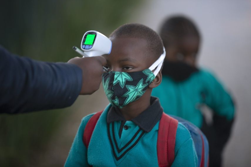 Un adulto comprueba la temperatura corporal de un alumno al regresar a la escuela en Johannesburgo, el martes 7 de julio de 2020, cuando se reabrieron más centros. Las escuelas habían cerrado en marzo en un intento de impedir contagios del nuevo coronavirus.&nbsp;