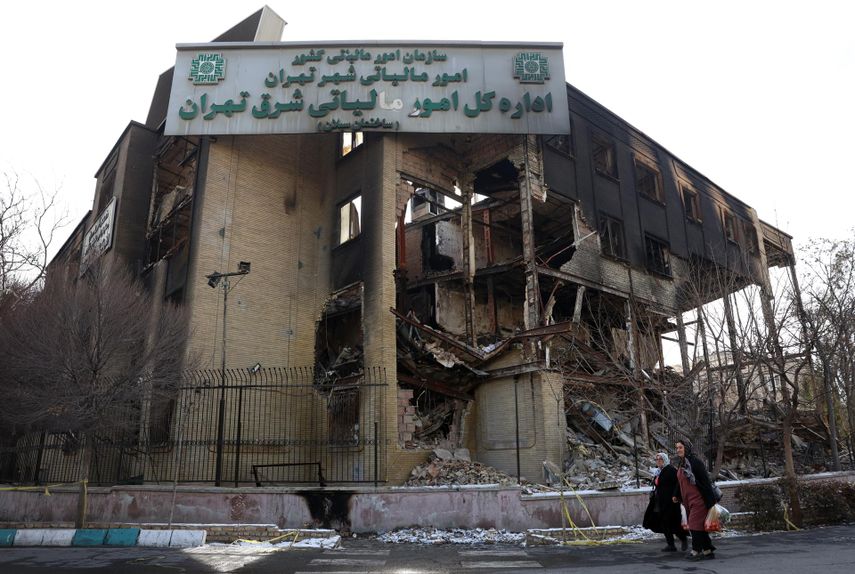 Residentes pasan junto al edificio de la oficina de impuestos, que se incendió durante las recientes protestas antigubernamentales en Teherán, Irán, el 21 de enero de 2026. Irán sufre un apagón nacional de internet que comenzó el 8 de enero de 2026, en medio de una creciente ola de protestas antigubernamentales.&nbsp;