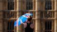 Una madre protege a su bebé del sol con un paraguas el martes 19 de julio de 2022, mientras camina por el puente de Westminster en Londres.