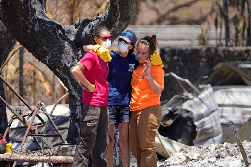 Tres mujeres se abrazan tras rebuscar entre los escombros de una vivienda destrozada por un incendio, el 11 de agosto de 2023, en Lahaina, Hawai.&nbsp;