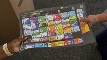 Un funcionario electoral entrega a un votante la papeleta de los candidatos presidenciales durante las elecciones generales en Santo Domingo, República Dominicana, el domingo 19 de mayo de 2024.&nbsp;