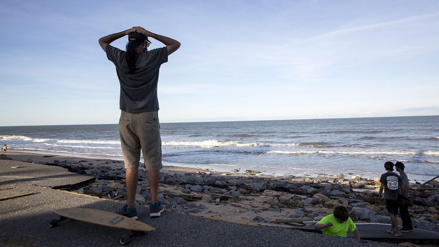 Un hombre mira el océano Atlántico con las manos en la cabeza desde los restos de una carretera devastada por la furia del huracán Matthew en Flagler Beach, Florida.