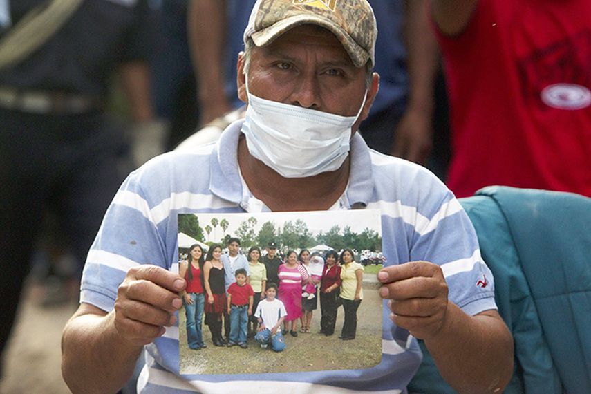 Un hombre sostiene la foto de su familia desaparecida después de un deslave que dejó hasta el momento 350 desaparecidos en Santa Catarina Pinula (Guatemala). (EFE)