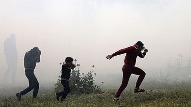 Varios palestinos huyen de gases lacrimógenos durante los enfrentamientos con soldados israelíes en el este de Beit Hanun, norte de la&nbsp;Franja&nbsp;de&nbsp;Gaza.&nbsp;