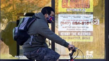 En esta foto del 6 de noviembre del 2020, un hombre pasa en su bicicleta junto a un negocio cerrado en Wilmette, Illinois. Con más encierros inminentes y meses antes de la amplia distribución de una vacuna, gobernadores en Estados Unidos están pidiendo más ayuda federal para el que se anuncia como un invierno sombrío.