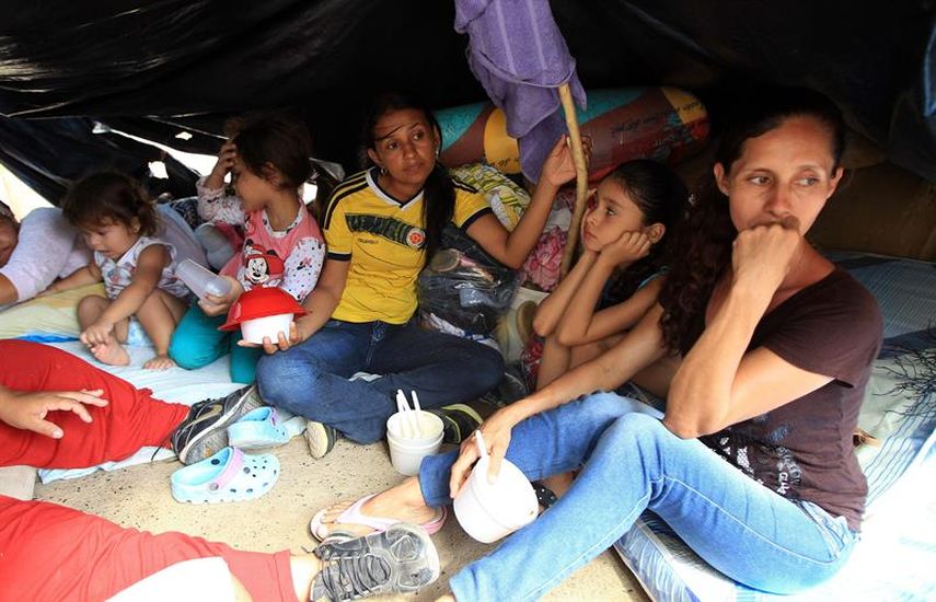 Colombianos que han retornado voluntariamente desde Venezuela permanecen con sus pocas pertenencias bajo un plástico en la Playa, sector de La Parada, Colombia. (EFE)