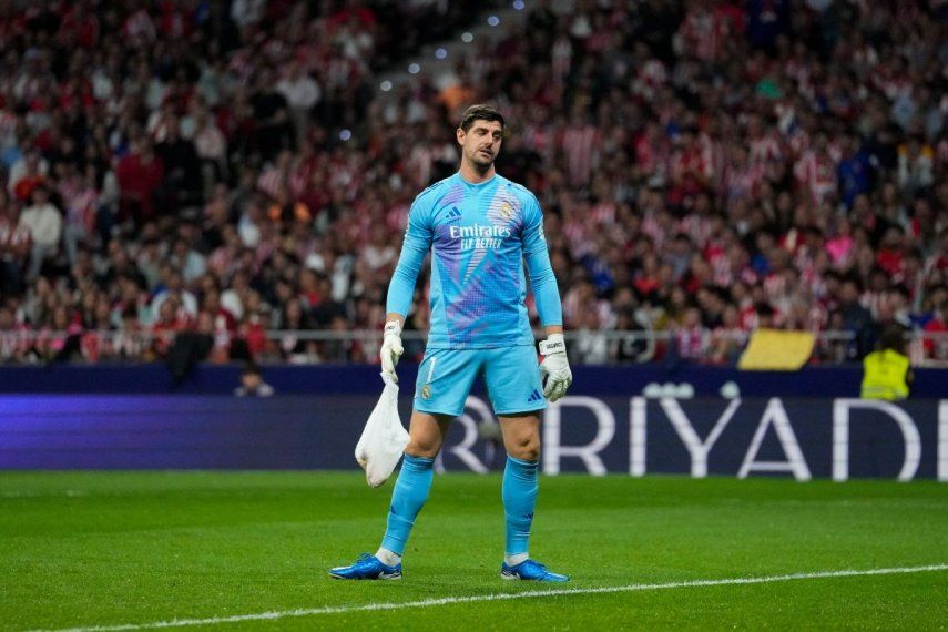 El arquero del Real Madrid, Thibaut Courtois, carga una bolsa arrojada por hinchas del Atlético de Madrid durante el partido contra su club, el domingo 29 de septiembre de 2024.