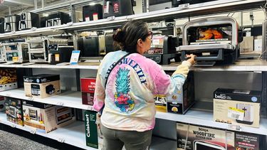 Una señora chequea los precios de productos electrodomésticos.