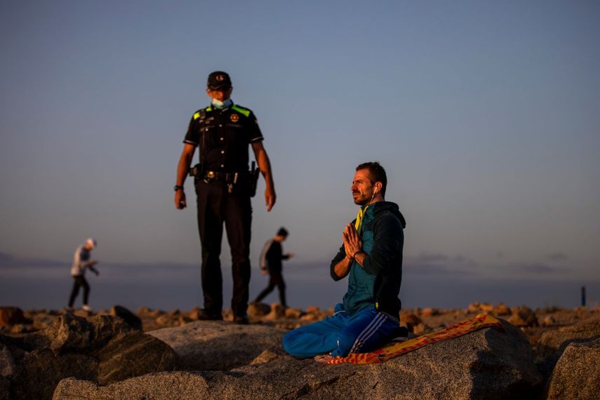 Un agente de polic&iacute;a habla con un hombre en una playa reabierta para actividades deportivas en Barcelona, Espa&ntilde;a, el viernes 8 de mayo de 2020.&nbsp;