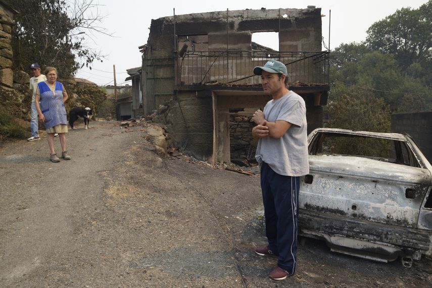 Samuel, vecino de A Caridade (Cualedro) delante de su casa destruída por el fuego, igual que propiedades de sus vecinos Dosinda y José Antonio.