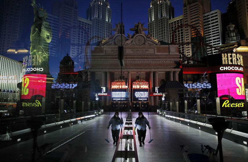 En imagen del 18 de abril de 2020, una trabajadora con cubrebocas limpia una acera entre casinos y otros negocios cerrados por el brote del nuevo coronavirus en Las Vegas.&nbsp;