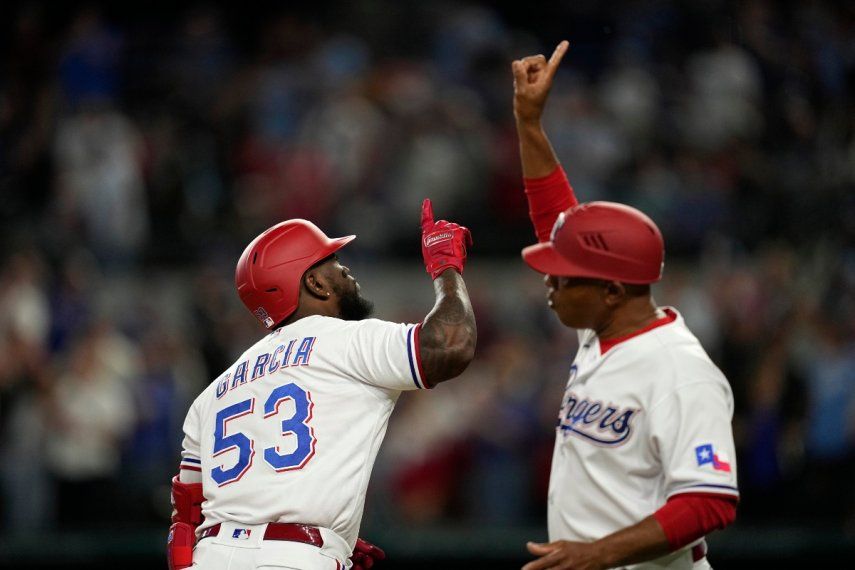 El cubano Adolis García (53) de los Rangers de Texas y el entrenador de tercera base Tony Beasley, a la derecha, celebran mientras Díaz se dirige a casa después de conectar un grand slam en la sexta entrada de un juego de béisbol contra los Reales de Kansas City, el 10 de abril de 2023, en Arlington, Texas.&nbsp;