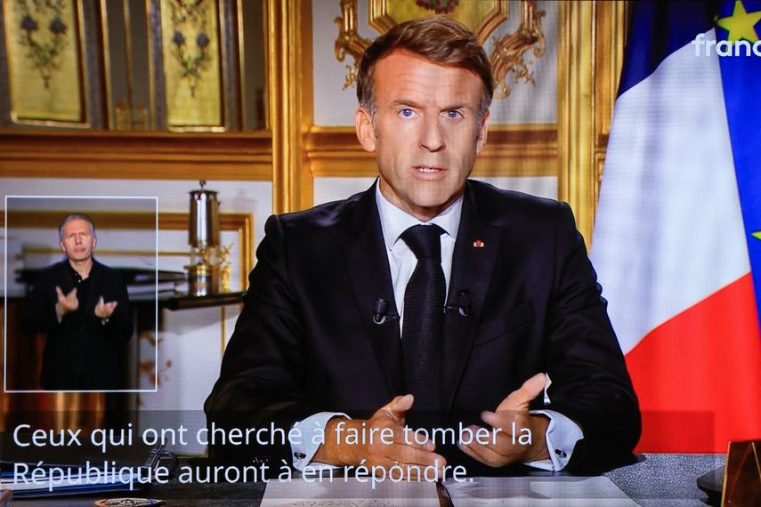 Esta fotografía muestra un monitor de televisión que transmite al presidente de Francia, Emmanuel Macron, pronunciando un discurso desde el Palacio del Elíseo, el día después de que se produjeran disturbios y saqueos en el marco de las protestas a nivel nacional contra el «alto costo de la vida», en París, el 18 de octubre de 2026.