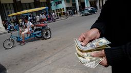 Una persona muestra dólares estadounidenses frente a un banco en La Habana, Cuba.&nbsp;