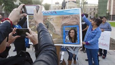 Erika Andiola se toma una foto en un cartel que simula ser una licencia de manejo frente al Congreso estatal de Arizona, en Phoenix, el 17 de diciembre de 2014.(AP) 