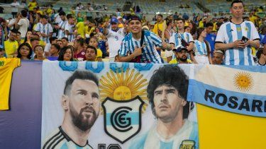 Hinchas alientan frente a una pancarta con la imagen del delantero argentino Lionel Messi y el fallecido astro Diego Maradona previo al partido entre Argentina y Brasil por las eliminatorias del Mundial, el martes 21 de noviembre de 2023, en Río de Janeiro.