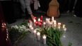 Una mujer pone una vela mientras la gente se reúne para una vigilia en honor a las víctimas del accidente de tren de alta velocidad del 18 de enero, que causó la muerte de 45 personas en Adamuz, el 25 de enero de 2026, en la estación de tren de Huelva (España)