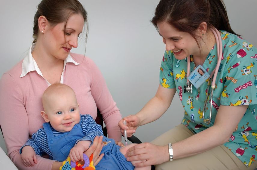 Una trabajadora de la salud administra vacuna a bebé.