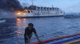 En una imagen proporcionada por la guardia costera de Filipinas, un hombre empuja un bote cerca del ferry filipino M/V Esperanza Star que se incendia en aguas frente a Panglao, en la provincia Bohol, Filiínas, el domingo 18 de junio de 2023.&nbsp;
