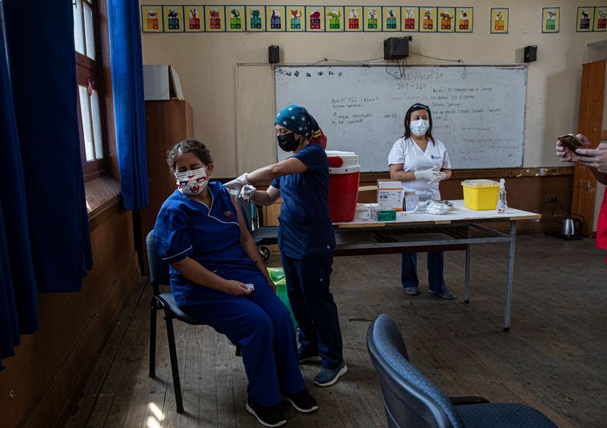 Una maestra recibe la primera dosis de la vacuna CoronaVac para COVID-19, de la china Sinovac Biotech, en la escuela pública Salvador Sanfuentes durante el inicio de la inmunización a los educadores en Santiago de Chile, el lunes 15 de febrero de 2021. El gobierno apunta a vacunar maestros y trabajadores administrativos escolares en todo el país antes del inicio del año escolar el 1 de marzo.